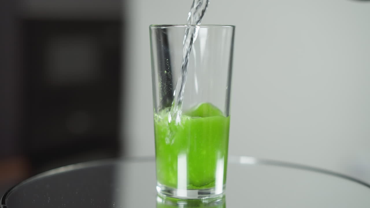 agua clara vertiendo en un vaso con una rebanada de kiwi, burbujas efervescentes en luz brillante