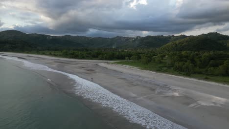 Coastal-beach-and-mountain-scenery-in-Lombok,-Indonesia-with-moody-clouds-in-the-background,-aerial