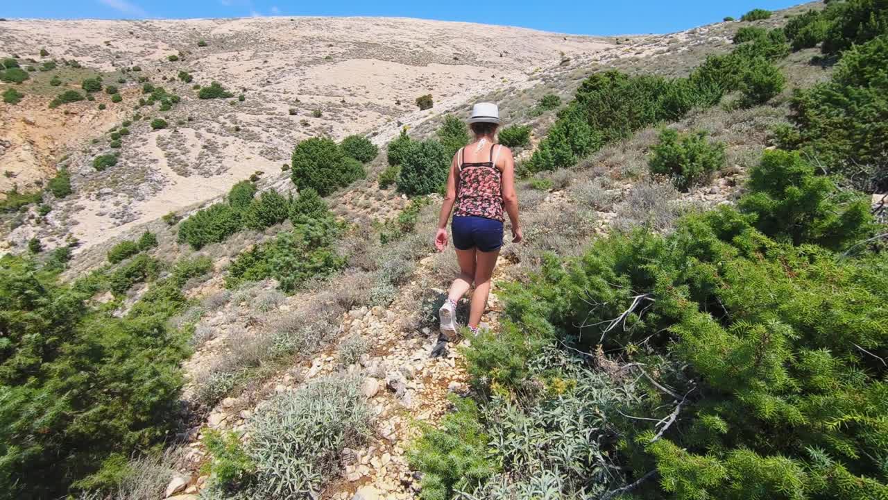 woman walking on rocky hill with beautiful bay sea view, Krk Island. Dolly shot