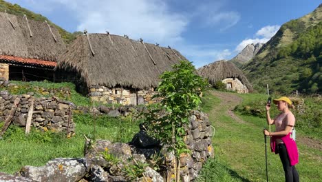 panorámica de mano a la derecha revelando a una mujer fotografiando cabañas en el pueblo del valle de somiedo, asturias