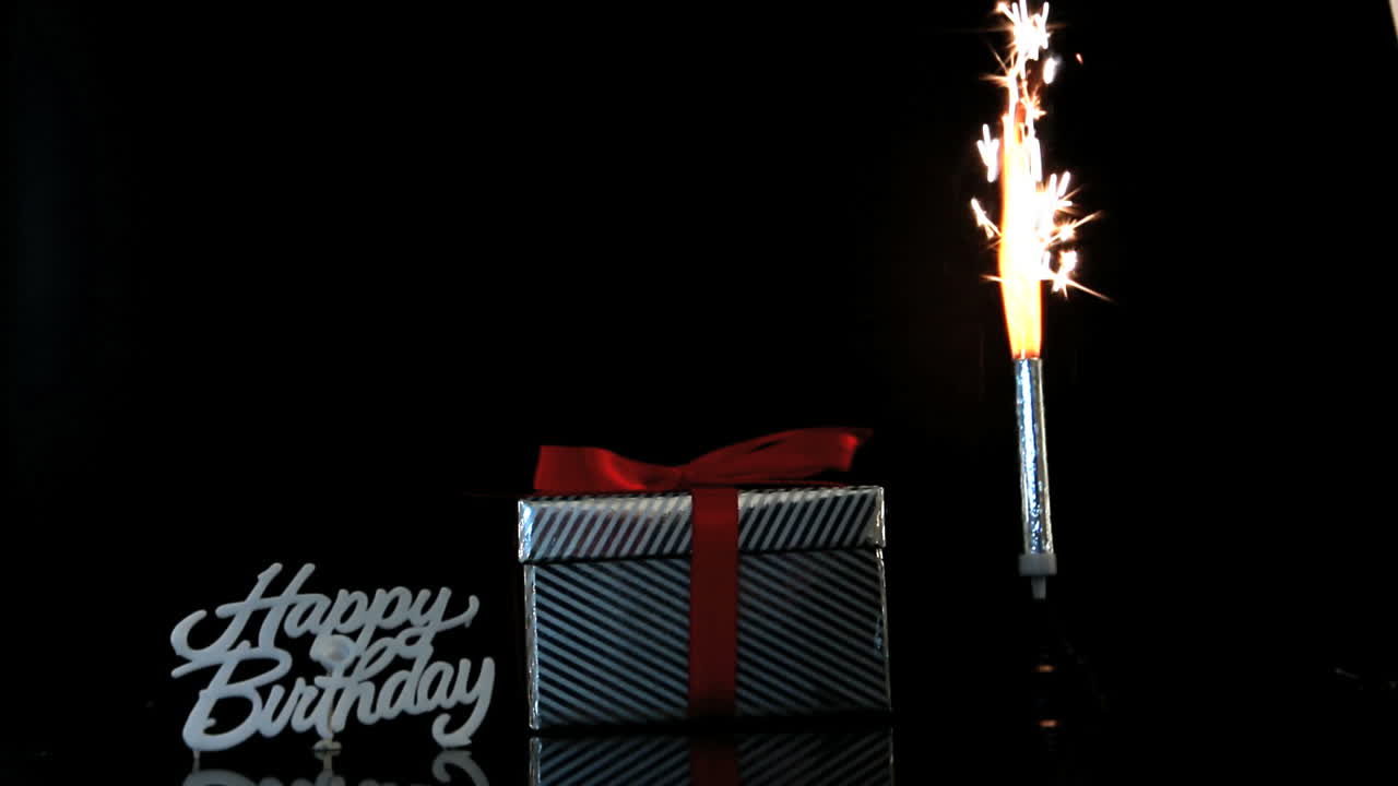 chispa ardiendo junto al regalo y el letrero de feliz cumpleaños