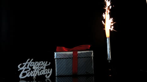 sparkler burning beside gift and happy birthday sign