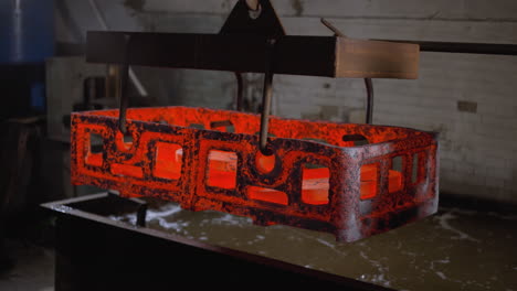 glowing hot metal casting being transported in an industrial foundry