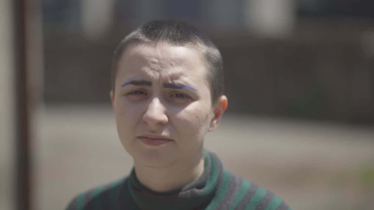 A Lesbian Looking At The Camera While Walking Under The Sun With Blurry Background - close up