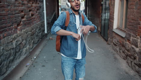 man dancing and listening to music in an alley