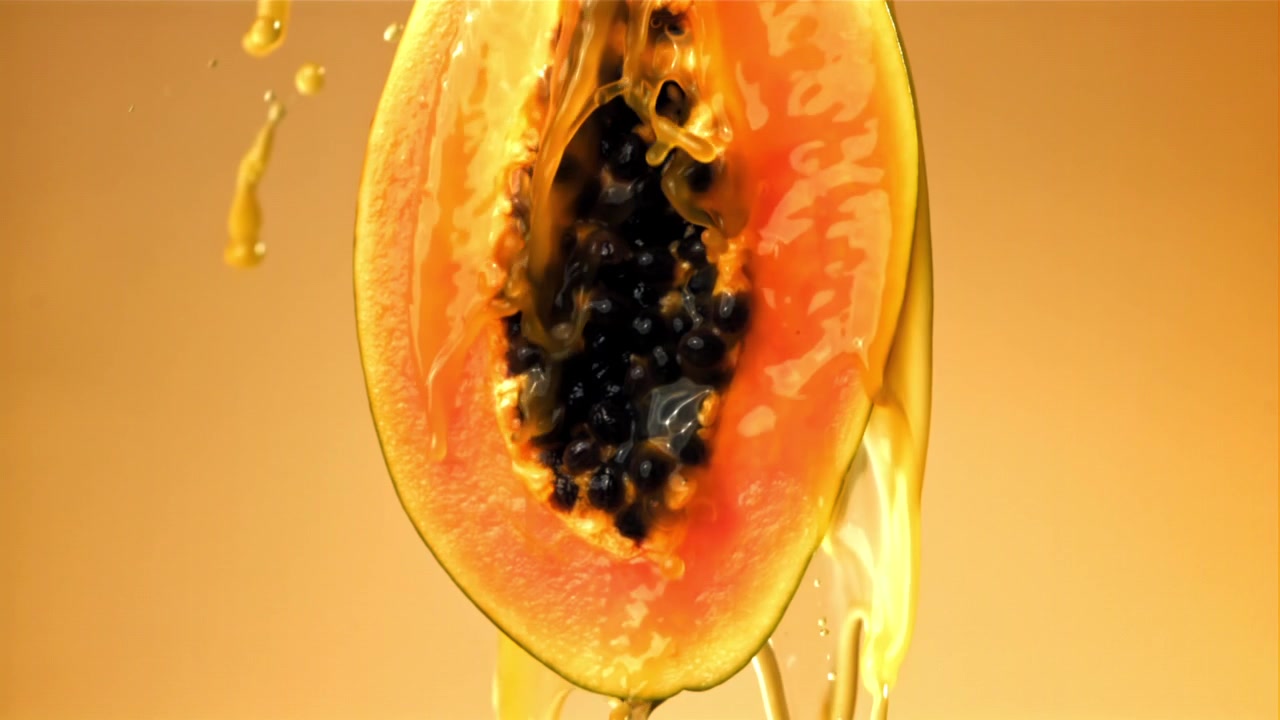 Juice helles i sakte film over en fersk papaya-halvdel.