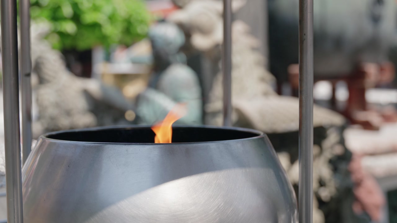 A sacred flame burning inside a polished metal vessel, often seen in Buddhist temples as a symbol of spiritual enlightenment, purity, and devotion