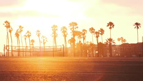 Una-Panorámica-Lenta-Y-Constante-De-Una-Puesta-De-Sol-Californiana-Con-Palmeras-Y-Canchas-De-Voleibol