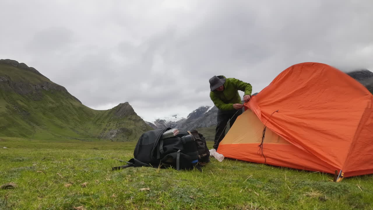 Timelapse: Camping couple set up orange tent in remote mountain valley