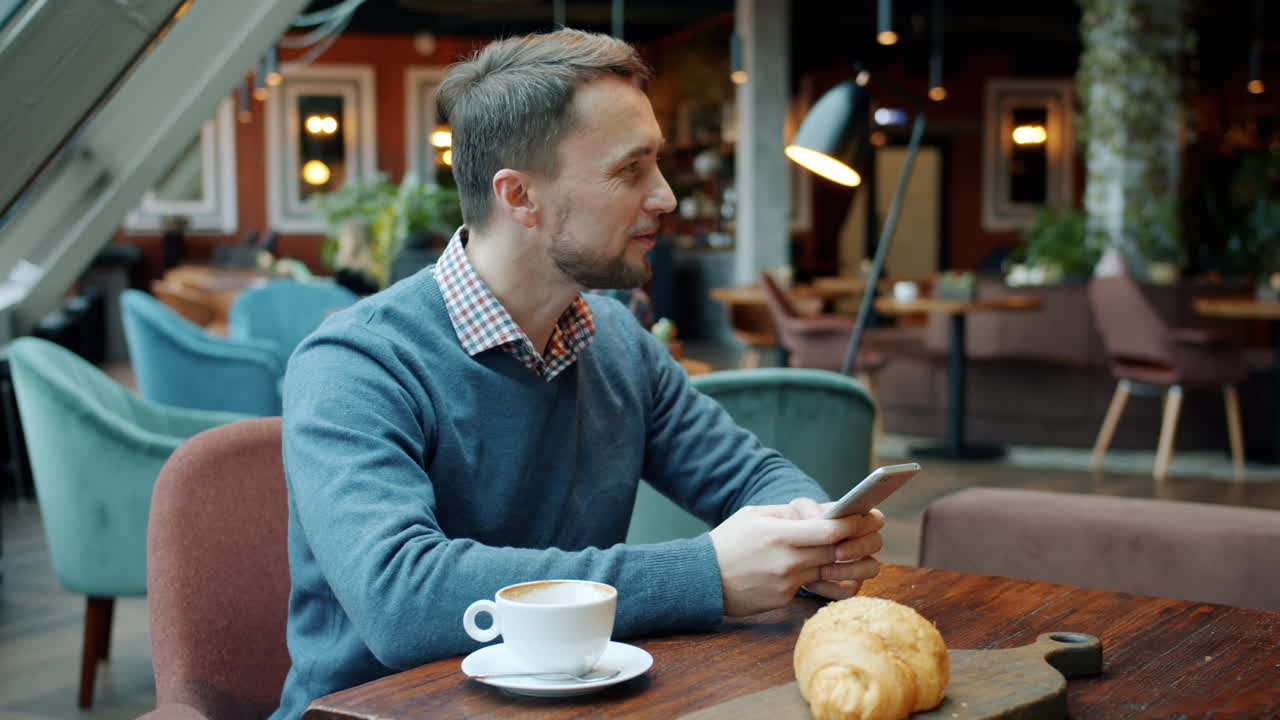 Man using smartphone in a cafe during breakfast