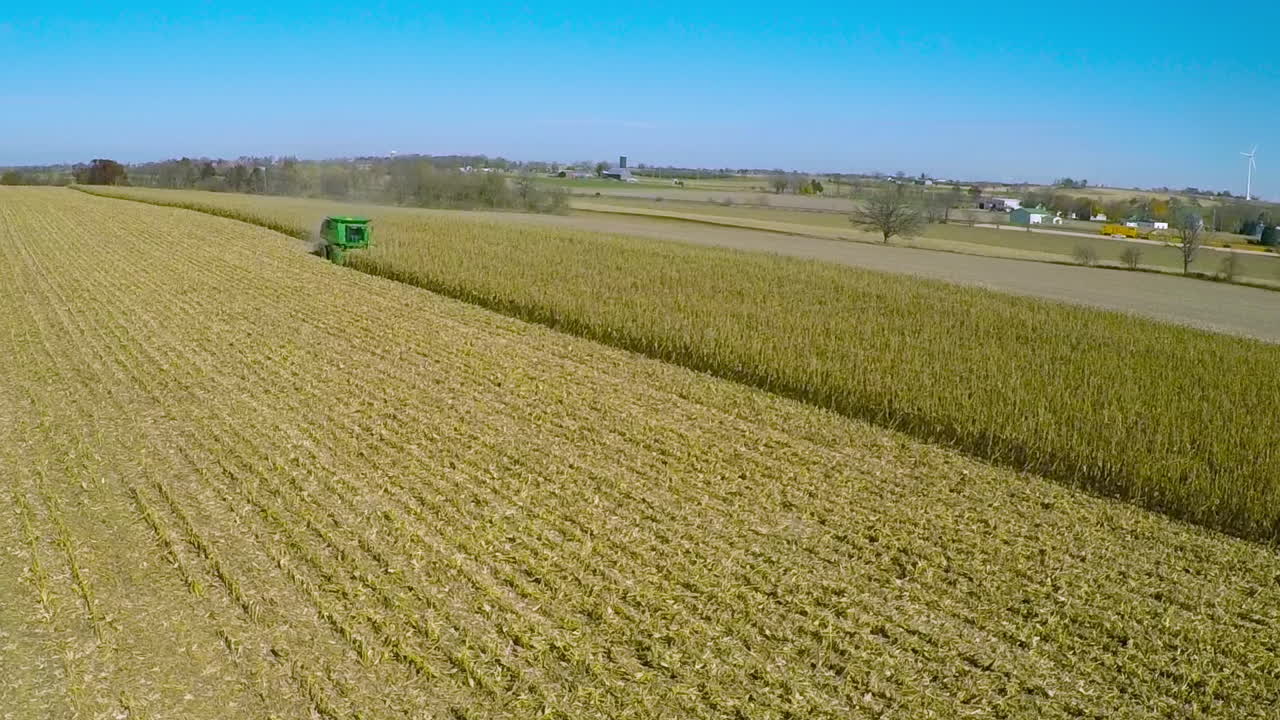 Ottima ripresa aerea su una fattoria rurale americana con mietitrebbiatrice per mais al lavoro nei campi