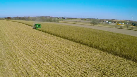excelente antena sobre una granja rural americana con cosechadora de maíz en el trabajo en los campos