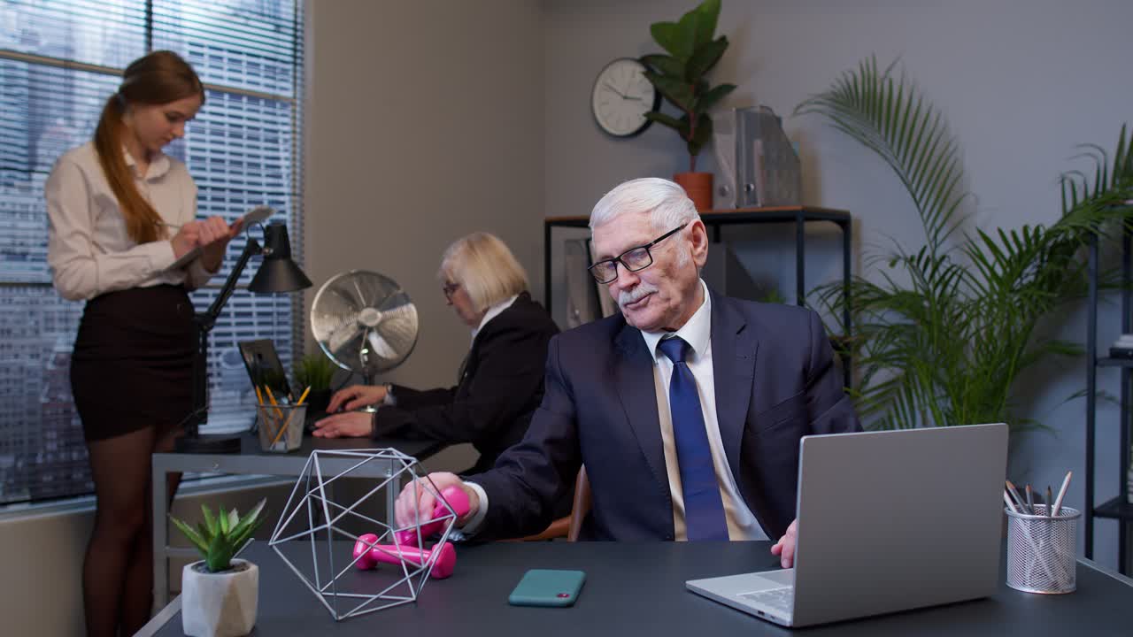 Business man making fitness dumbbells exercises after hard work while sits at office desk workplace