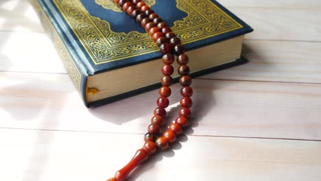 holy book quran and rosary on table, close up.