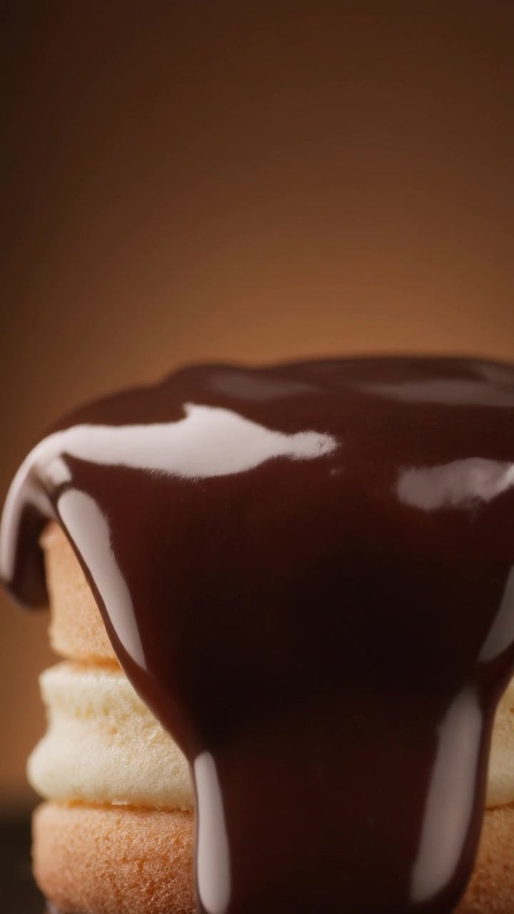 Primo piano di una glassa al cioccolato fondente che cola su una mini torta a strati