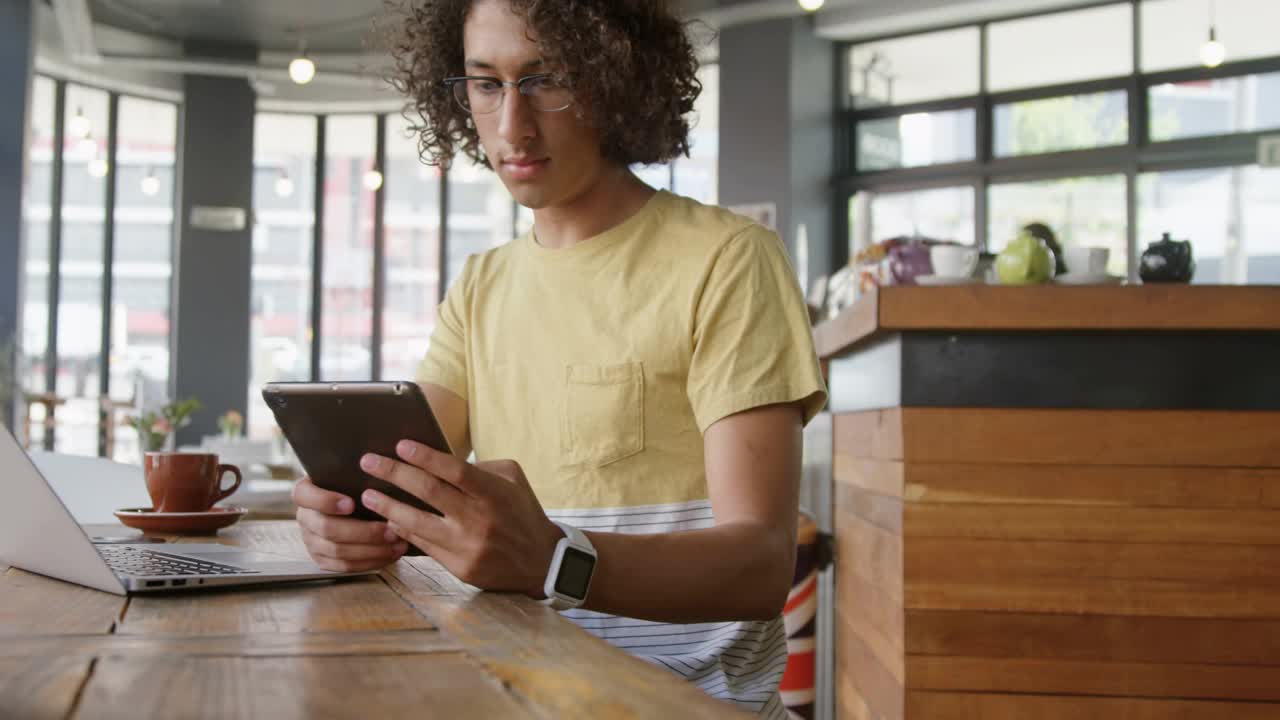 Adult male working on tablet and tapping, causing social notifs growing and drifting across laptop