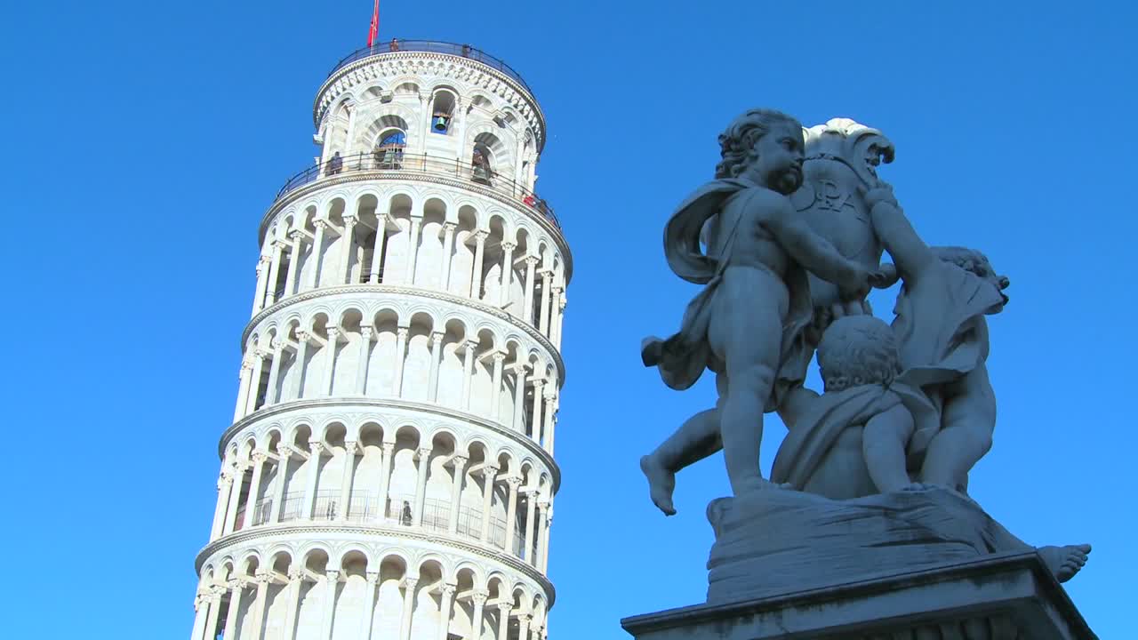 una estatua de ángeles cerca de la torre inclinada de pisa en italia