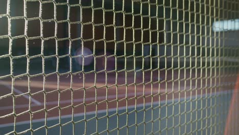 indoor tennis court viewed through netting