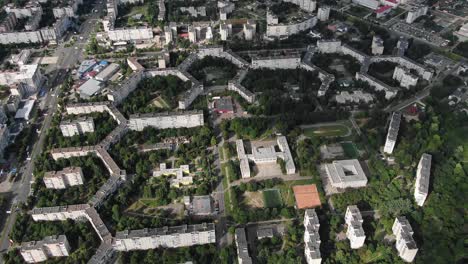 aerial view of geometrically shaped buildings in a city surrounded by trees