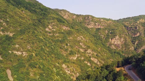 Tiro-Aéreo-Ascendente-Revela-La-Conducción-De-Automóviles-En-Carreteras-Sinuosas-De-Montaña-En-Barrancos-Escarpados-De-Las-Montañas-Rodope-Bulgaria