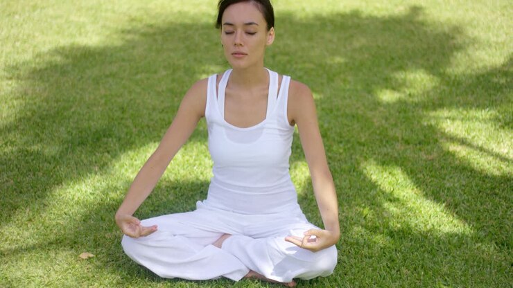 Pretty serene young woman meditating outdoors
