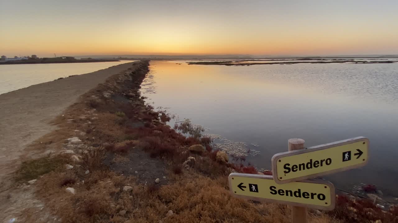Wooden sign showing the way of a trekking footpath in the marshes of cadiz.
