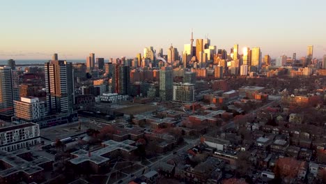 dolly drone shot flying towards downtown toronto over regent park during sunrise with blue skies.