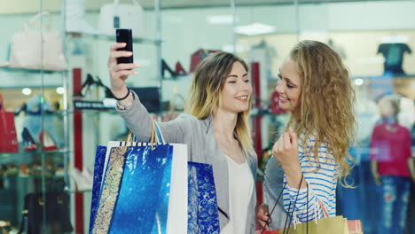 two friends in the store make selfie on a background of glass windows they are in the hands of a lot