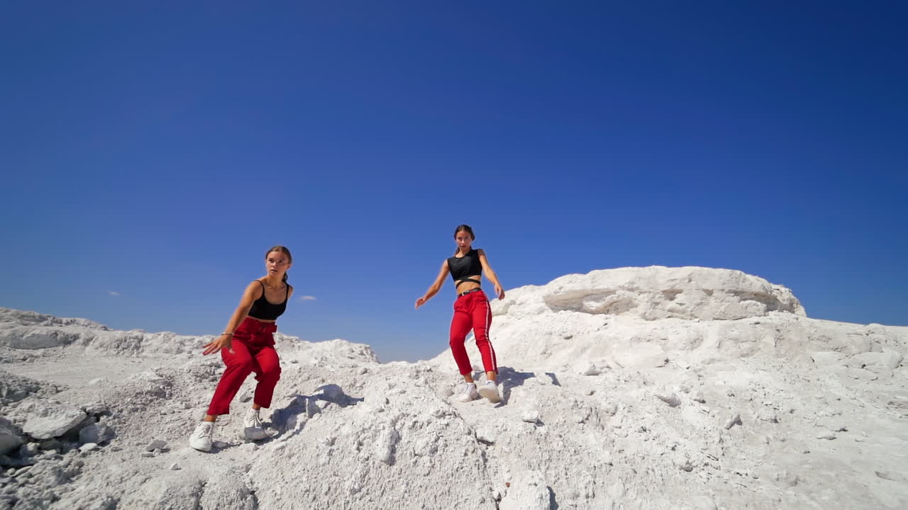 Two Women Posing in Red Pants and Black Tops in a White Landscape