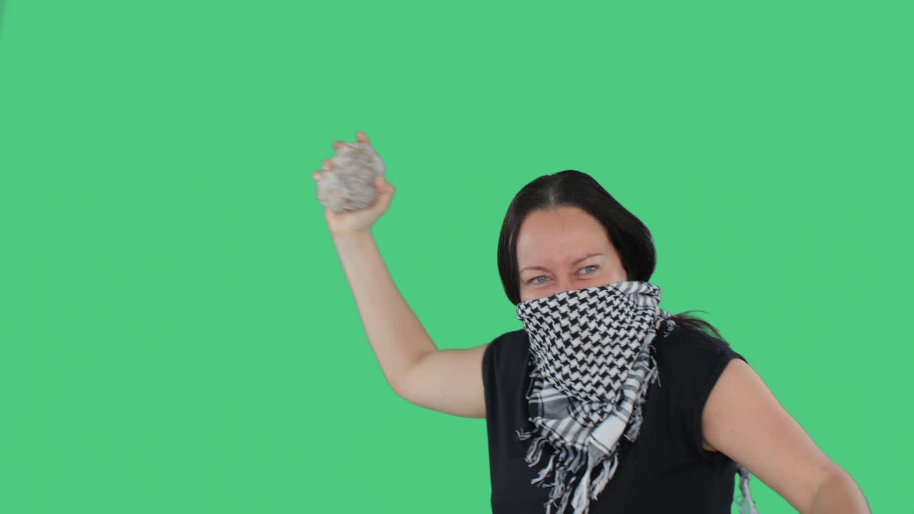 "녹색 배경의 전국 파업에서 손에 돌을 들고 분노하는 여성, 정치 혁명에 주먹과 돌을 보여주는 반다나를 입은 분노한 여성, 사람들이 집회하는 다리즘 개념."""