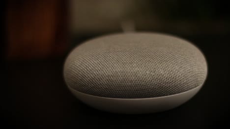 rack focus across a close up of a voice controlled mini smart speaker gadget