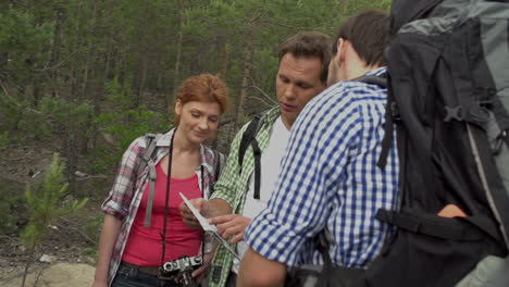 a group of mountaineers in the middle of the forest discusses where to go with a map