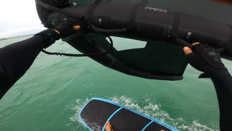 pov of a surfer standing and balancing on a board, wing foiling in the sea at summer