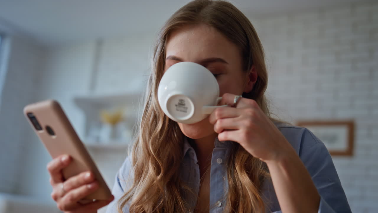 Girl scrolling news feed at smartphone kitchen closeup. Woman looking cellphone