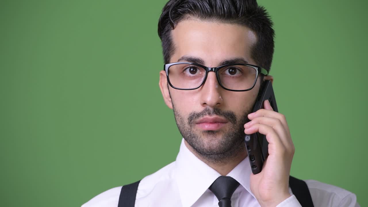 joven empresario persa barbudo y guapo contra un fondo verde