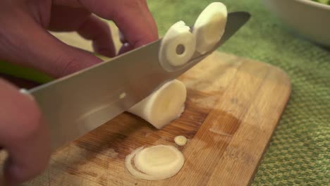 extreme close up male chef preparing fresh leeks, chopping them with a sharp knife to create a dish