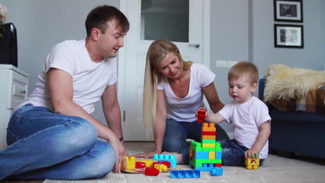 happy family dad mom and baby 2 years playing lego in their bright living room. slow-motion shooting happy family