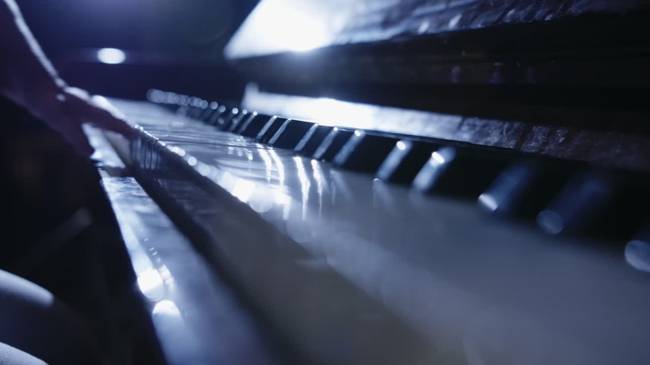 Gros plan sur des mains jouant du piano en basse lumière