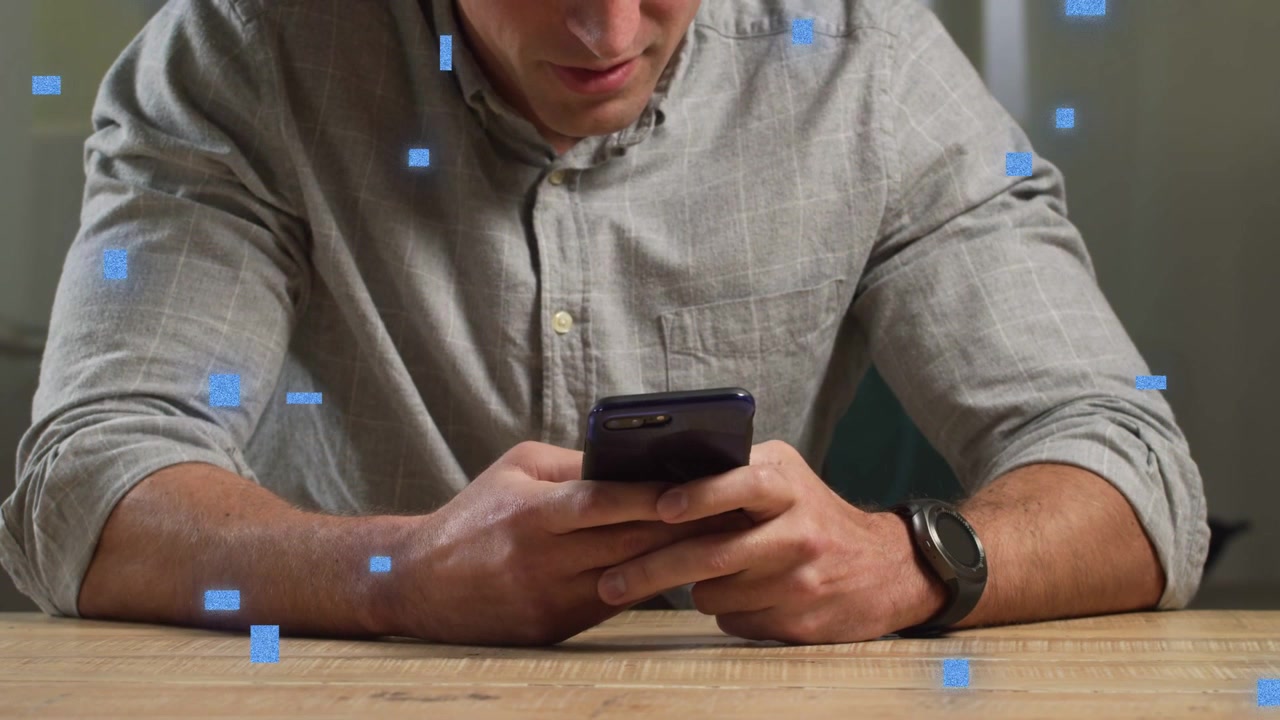 Uomo che usa lo smartphone al tavolo, navigando contenuti tecnologici mentre quadrati blu fluttuano senza toccarsi.