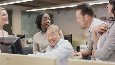 Diverse-team-of-business-people-working-late-brainstorming-around-computer-touchscreen