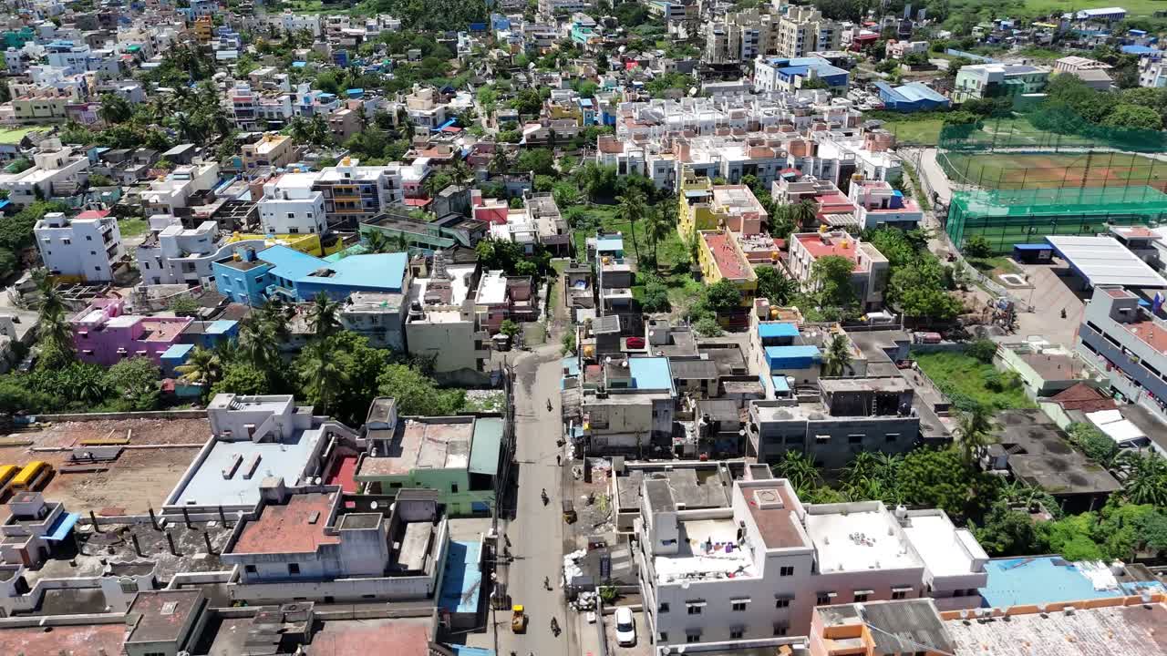 Urbanization and Growth: Elevated view capturing the expansion of a large city, featuring a mix of colorful residential buildings and commercial structures. A visible sports court, cloud-filled sky