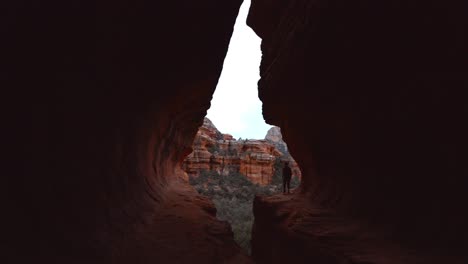 female hiker walks out on dramatic edge at boynton canyon subway in sedona