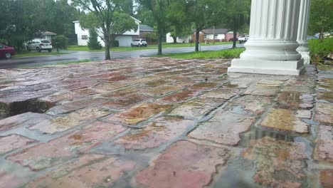 rain drops on brick pavement, long shot, rainy weather, cars and houses in background.