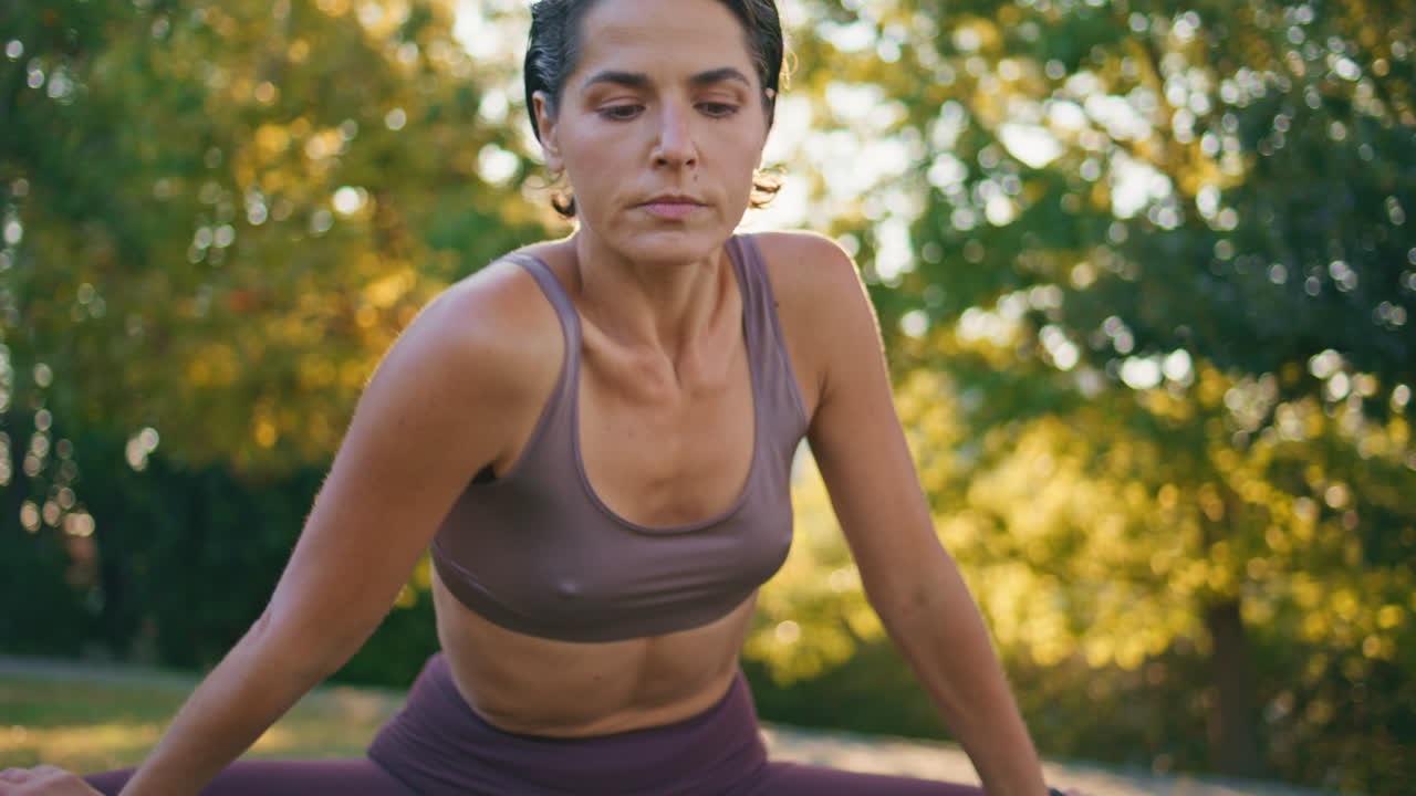 mujer flexible doblando el cuerpo en el parque solar de primer plano. deportista estirando los hombros