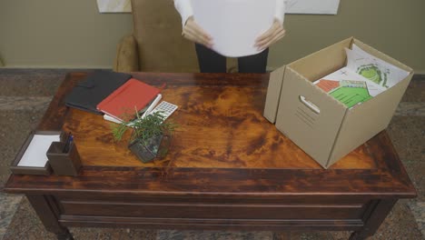 empleada seria empacando cosas de oficina después de la renuncia