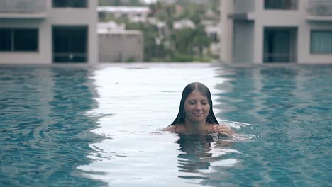 Eine-Anmutige-Frau-Taucht-In-Zeitlupe-Aus-Dem-Wasser-Des-Hotelpools-Auf