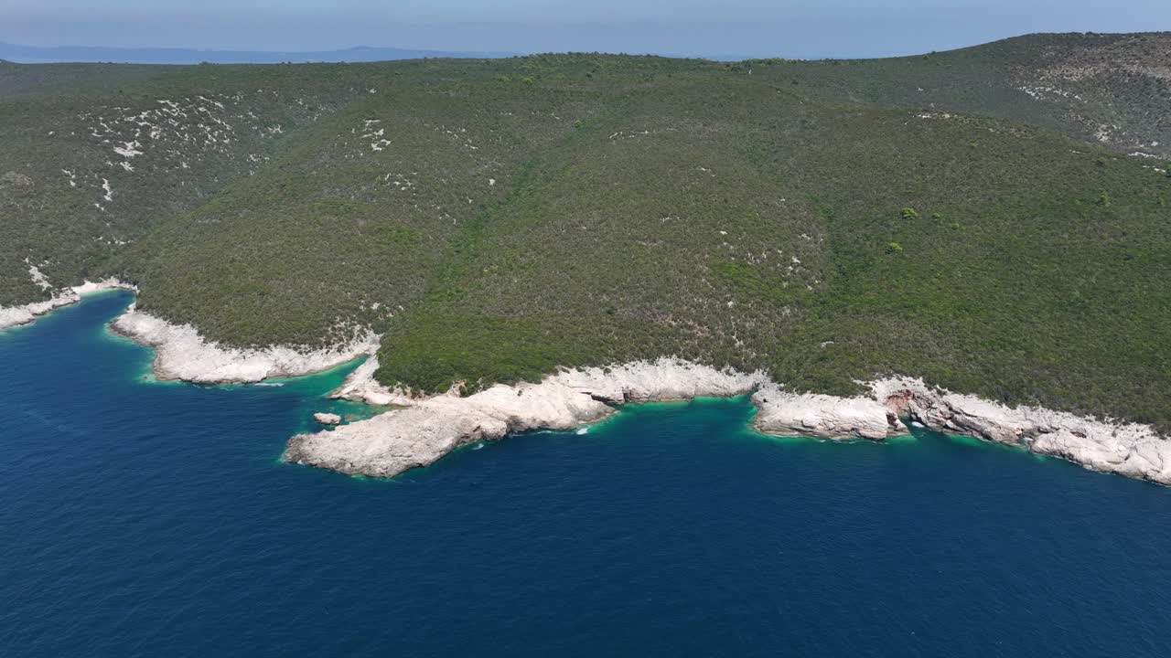 Rocky white shoreline with turquoise water coves and dense green forested hills near Dugi Otok, Croatia. Panoramic drone aerial