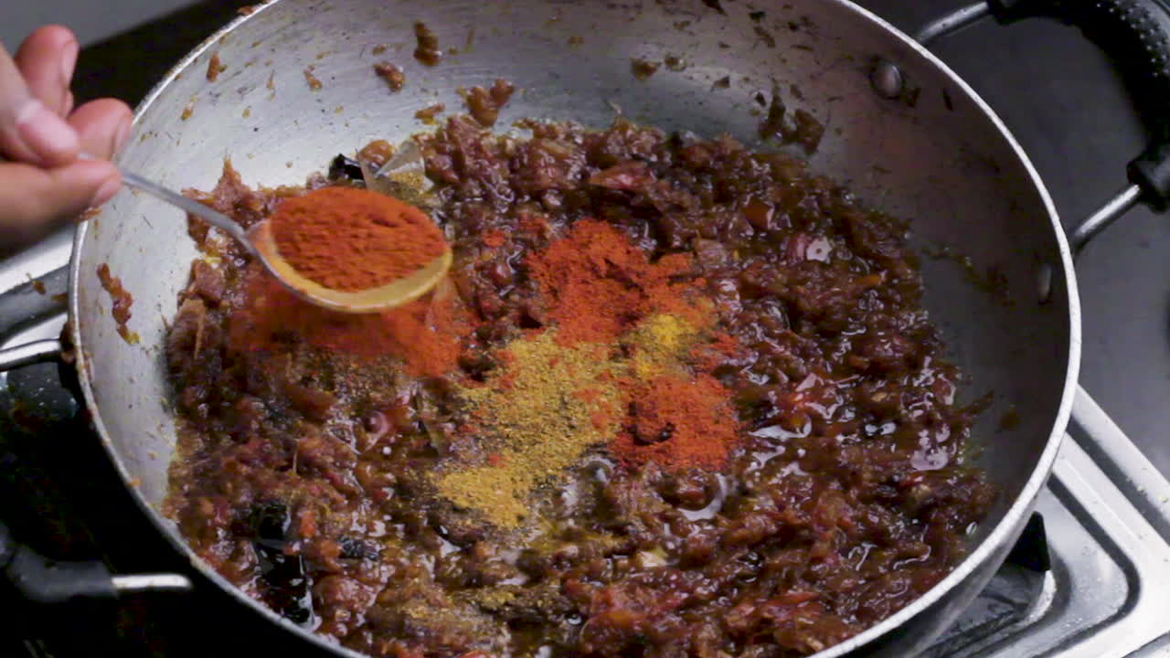 Close up shot of an Indian spicy Masala paste mixing in hot oil for food preparation.