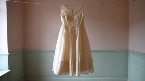 cream vintage dress hanging on a laundry line indoors