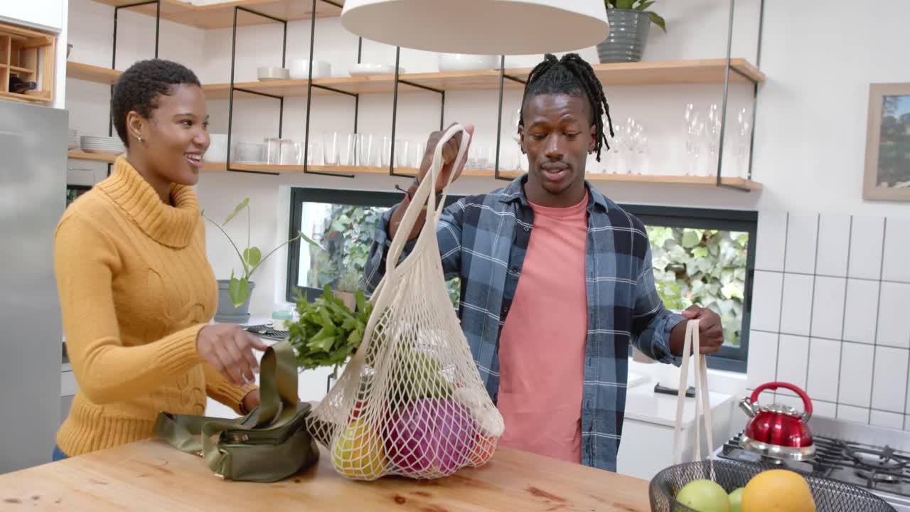 montaje de una feliz pareja afroamericana cocinando y relajándose en casa, en cámara lenta